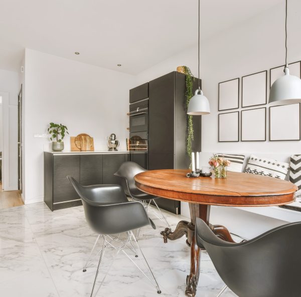 Modern kitchen with black cabinetry and dining area on marble flooring in a luxury apartment.