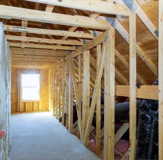 Renovated attic with wooden supports, a bright window, and a long hallway designed by AC Reformas