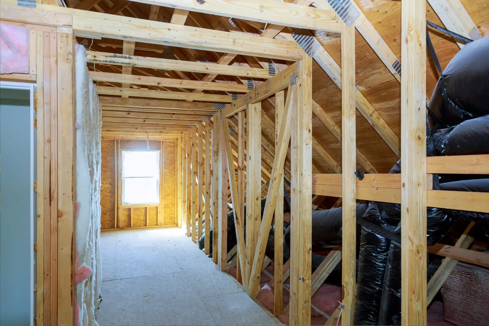 Renovated attic with wooden supports, a bright window, and a long hallway designed by AC Reformas